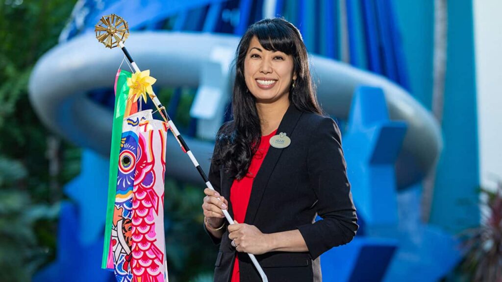 Allie standing in front of the Disneyland Hotel holding a carp flag