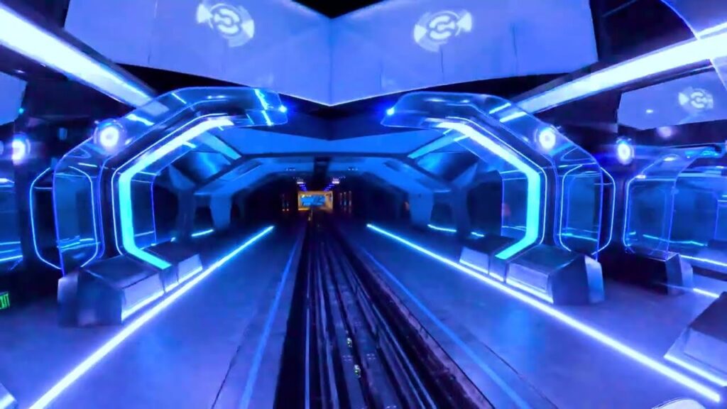 (ON-RIDE) TRON, Night POV, Magic Kingdom Walt Disney World | The ride shares similarities with "Guardians of the Galaxy" at EPCOT, they feature screen and lighting effects along an indoor track. This ride features a motorbike seat instead of a traditional car. An ADA-accessible vehicle is located on the back of select trains for riders requiring assistance or not fitting in the TRON vehicle because of size.