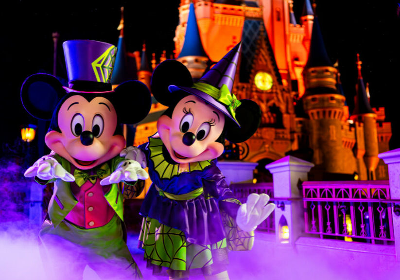 Mickey and Minnie pose in their Halloween outfits in front of Cinderella Castle