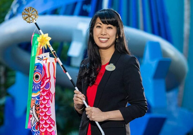 Allie standing in front of the Disneyland Hotel holding a carp flag